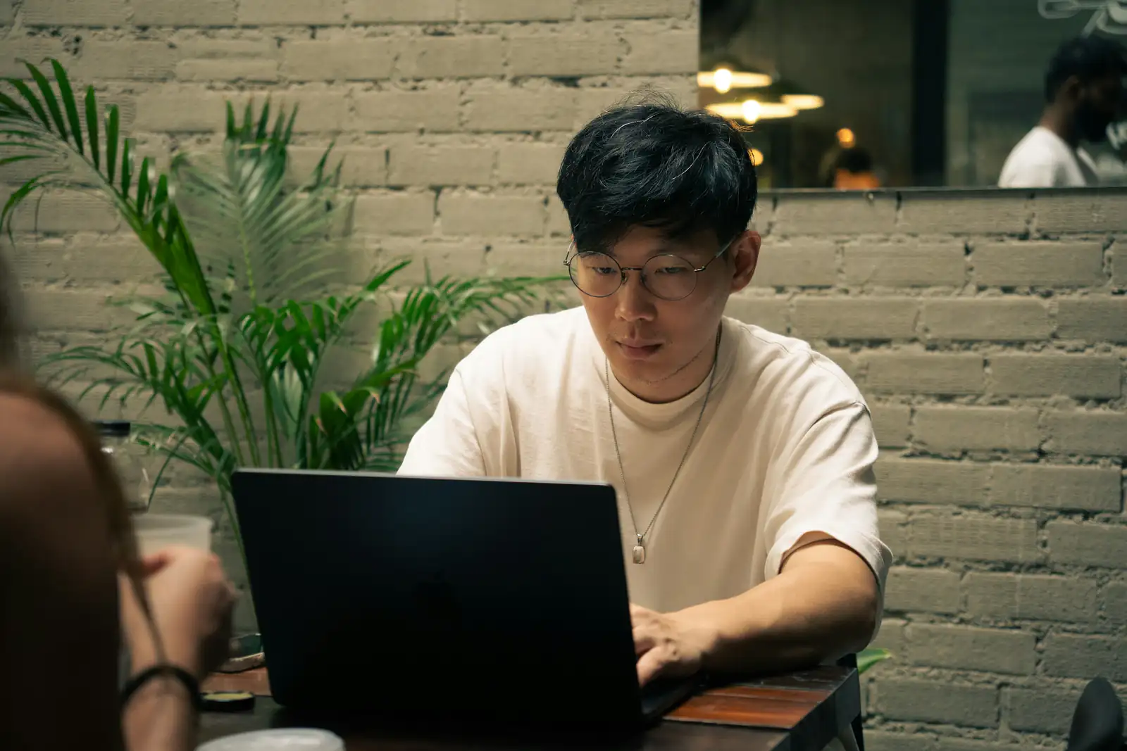 Un bărbat lucrând pe laptop într-o cafenea
