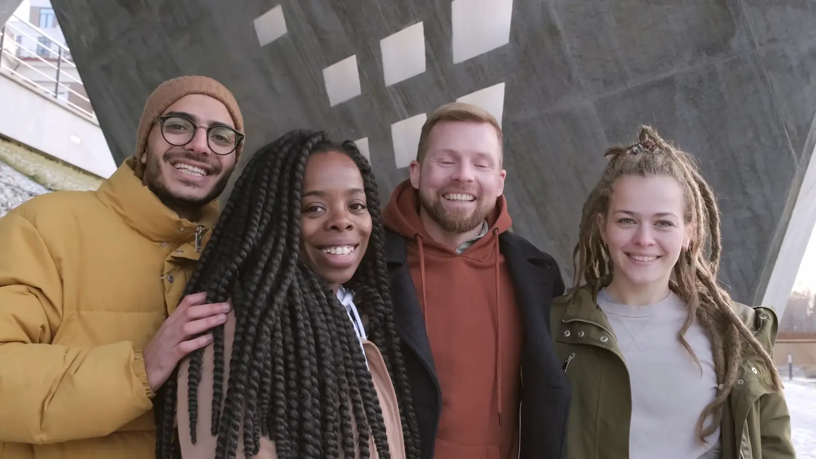 Four friends standing arm in arm, smiling and laughing