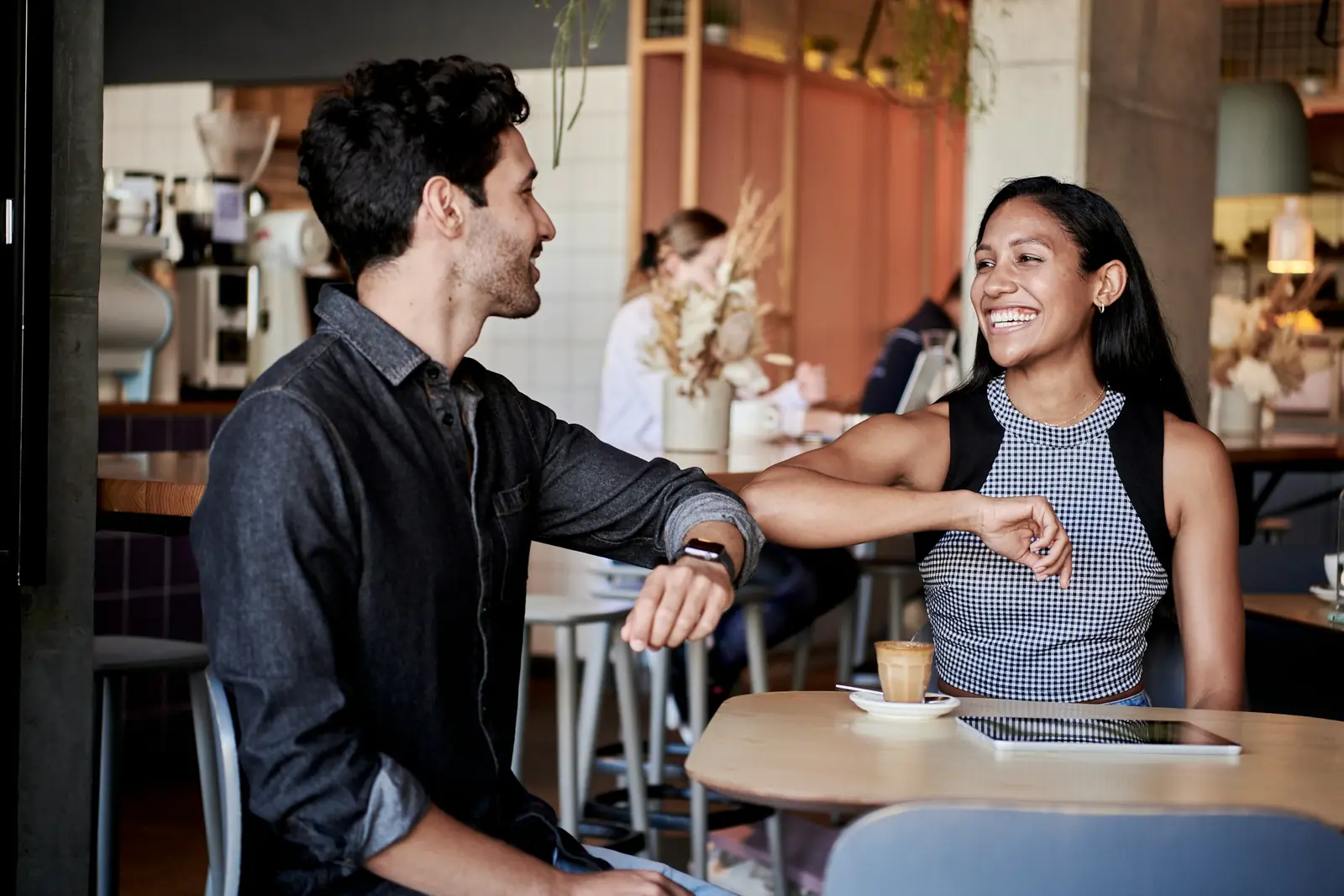 A man and a woman laughing together at a table in a bright café